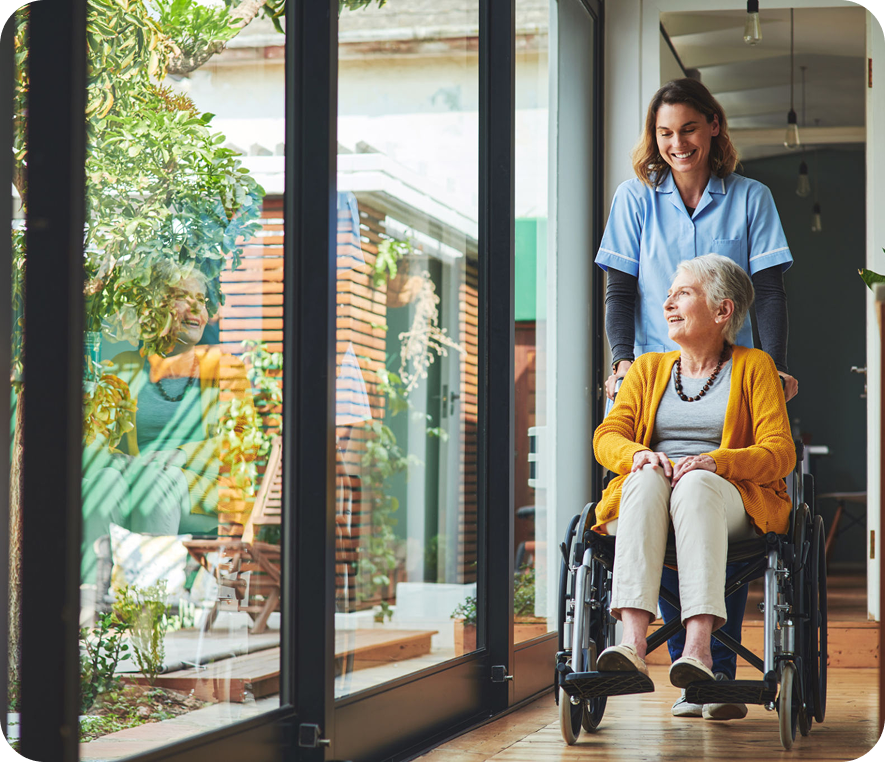 Smiling caregiver with elderly patient in wheelchair